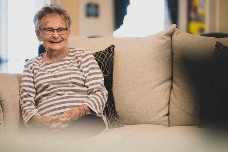 Resident smiling while sitting on a couch