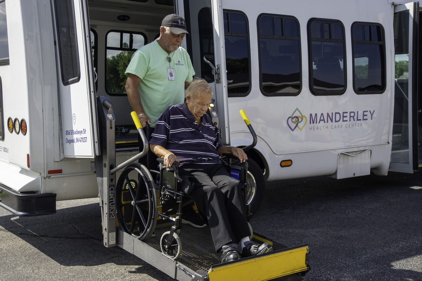 Staff assisting resident from a facility transport van