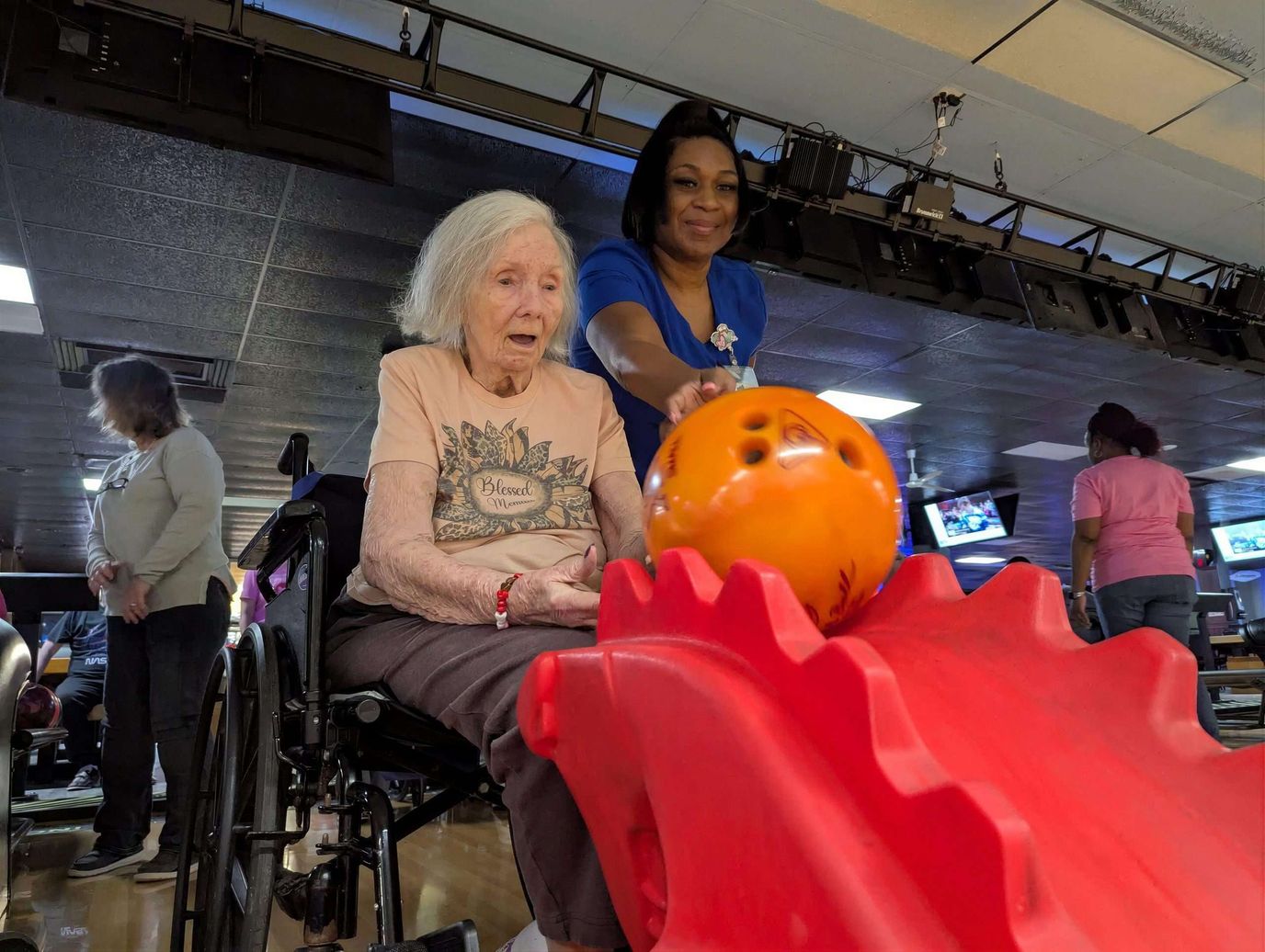 Residents enjoying a bowling activity with staff assistance