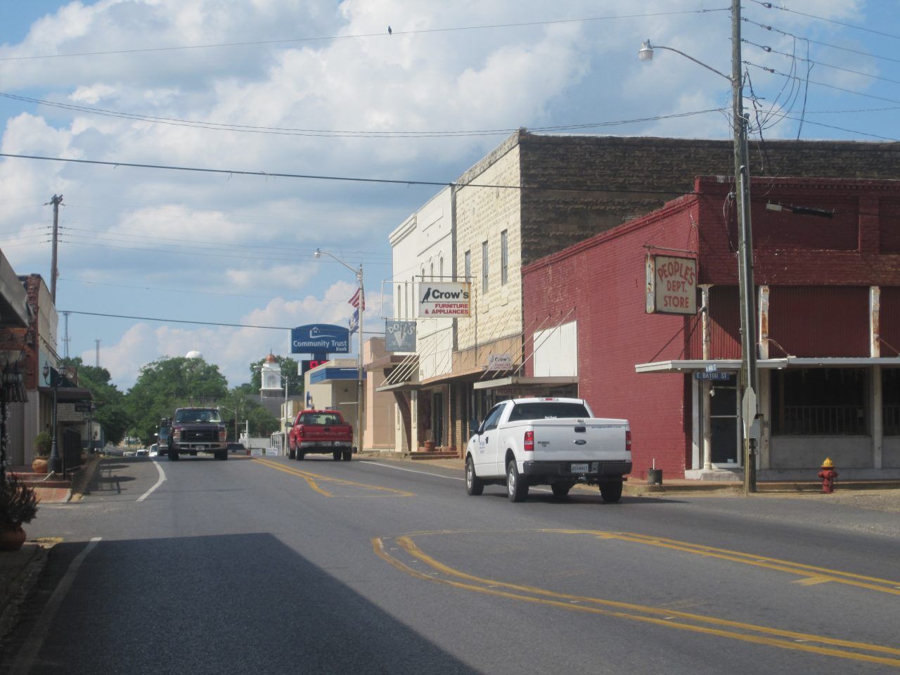 Arbor Lake Skilled Nursing & Rehabilitation, Nursing Home in Farmerville, LA — Main street of a small town with shops and vehicles