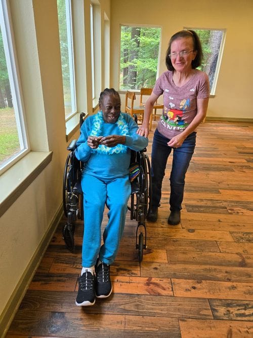 Princeton Place-Ruston, Nursing Home in Ruston, LA — Resident in a wheelchair with a staff member in a hallway