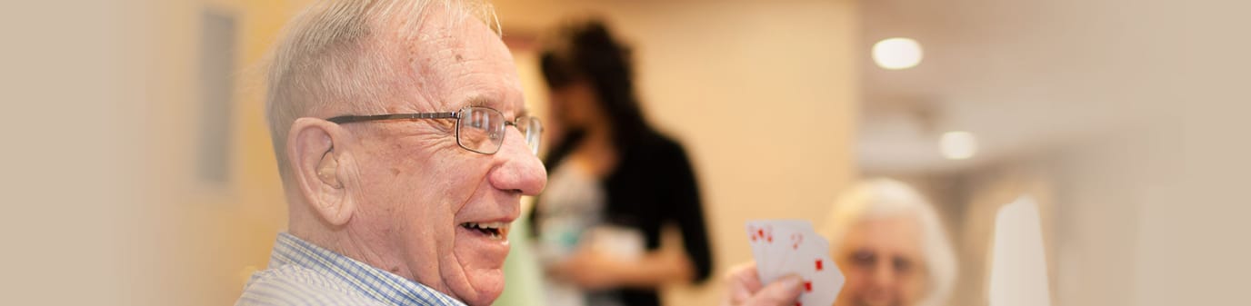 Holiday Retirement Village, nursing home in Evansville, IN — Senior resident playing cards with a joyful expression