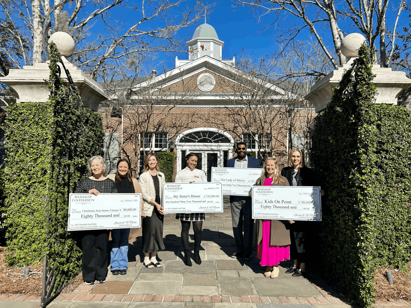 Residents and staff holding large checks outside the facility