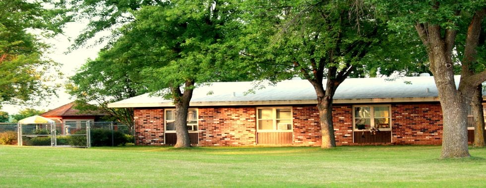 Dells Nursing and Rehab Center Inc., Nursing Home in Dell Rapids, SD — Brick building surrounded by green grass and trees