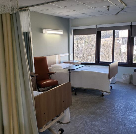 Private resident room with two beds and a chair