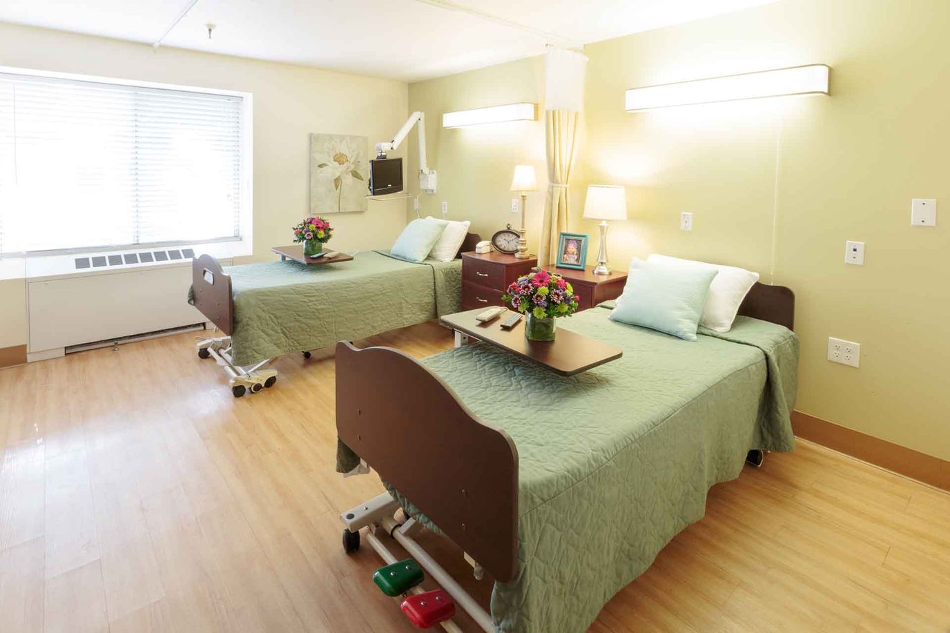 A bright and tidy resident room with two beds and floral decor
