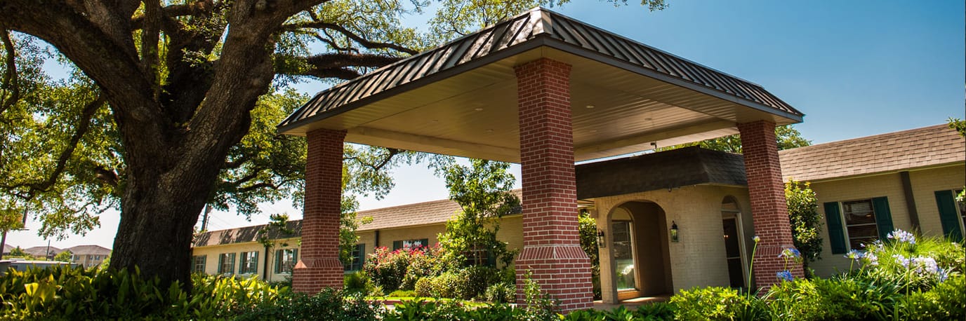 Exterior view of a senior living facility with large trees