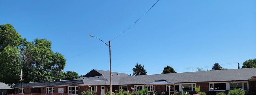 Elwood Care Center, Nursing Home in Elwood, NE — Senior living facility exterior with landscaping and clear blue sky