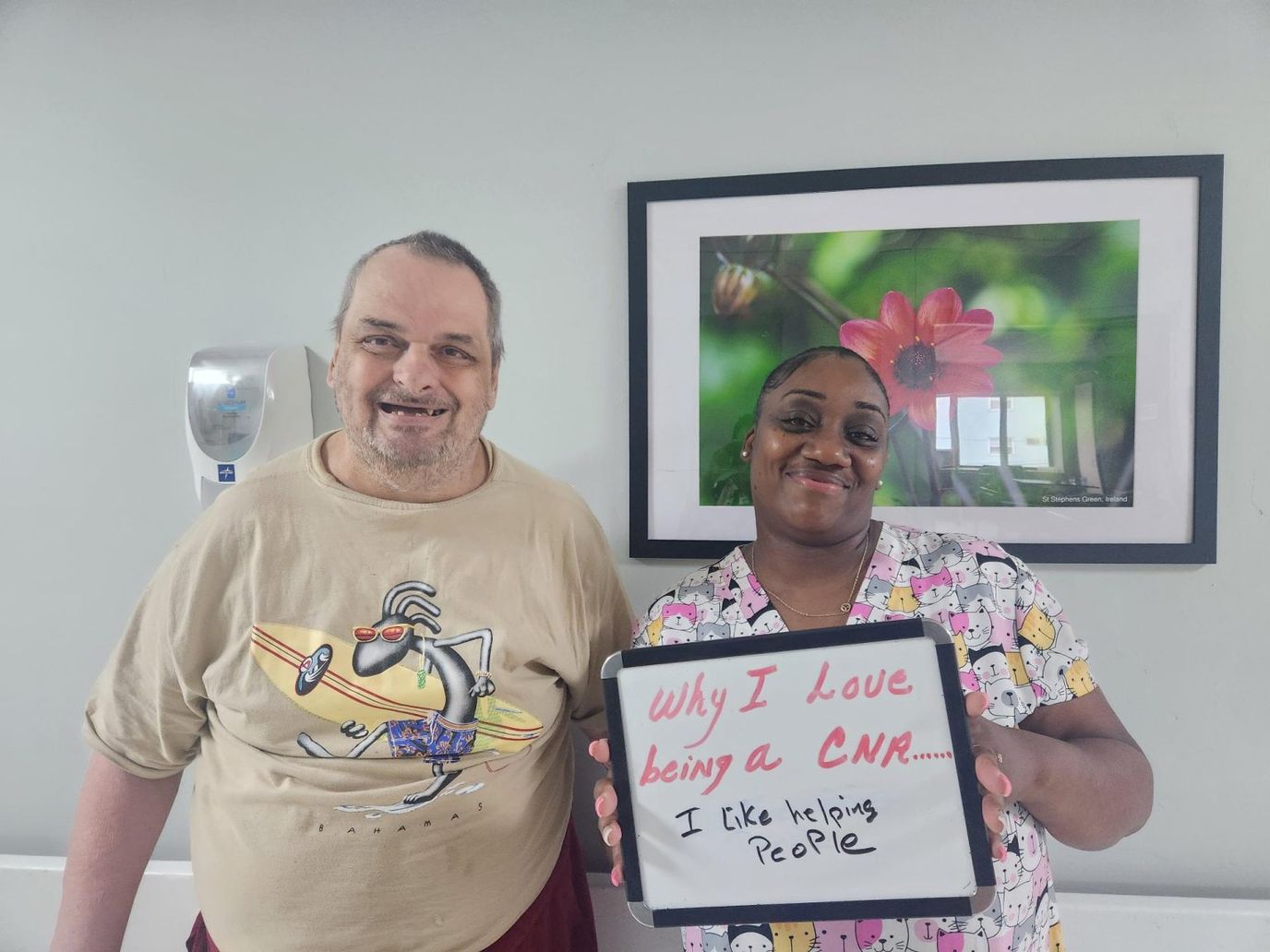 Resident and staff member smiling with a sign