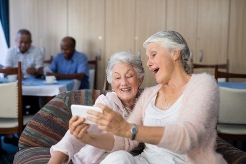 Two smiling women enjoying a moment together with a phone