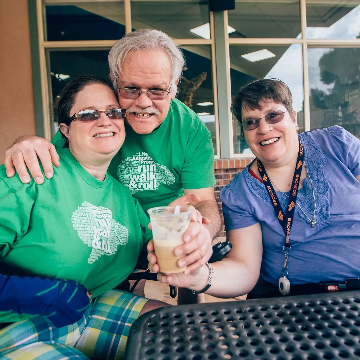 Three residents enjoying iced coffee on a patio.