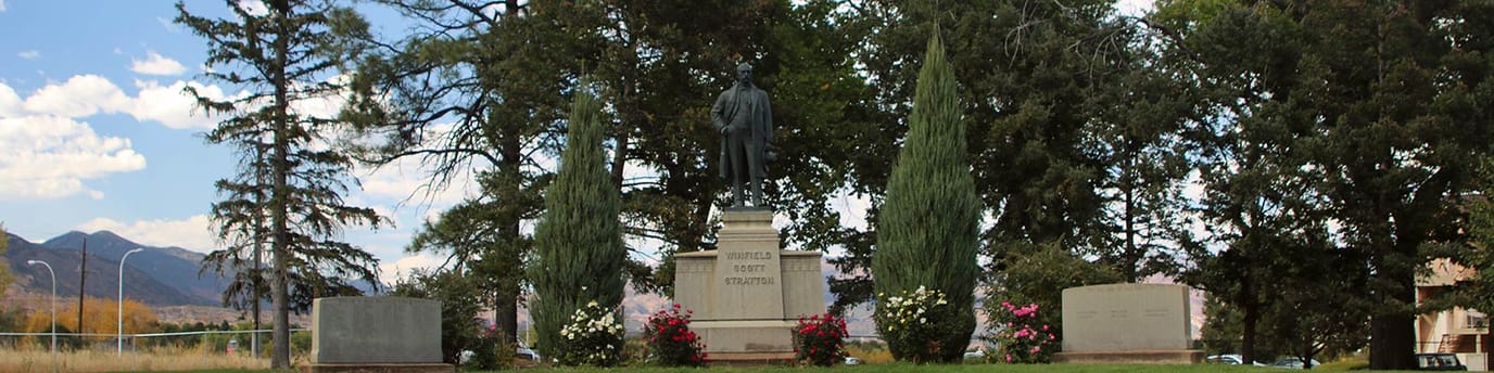 Statue surrounded by trees and flowers in an outdoor area
