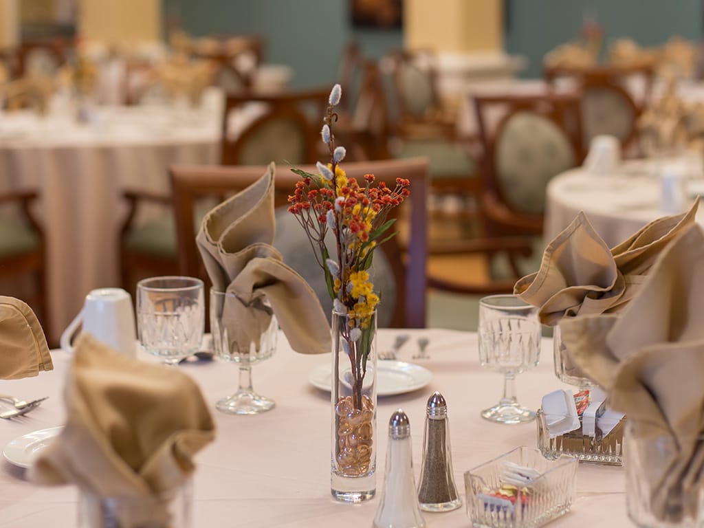 Dining area with elegantly set tables and flowers.