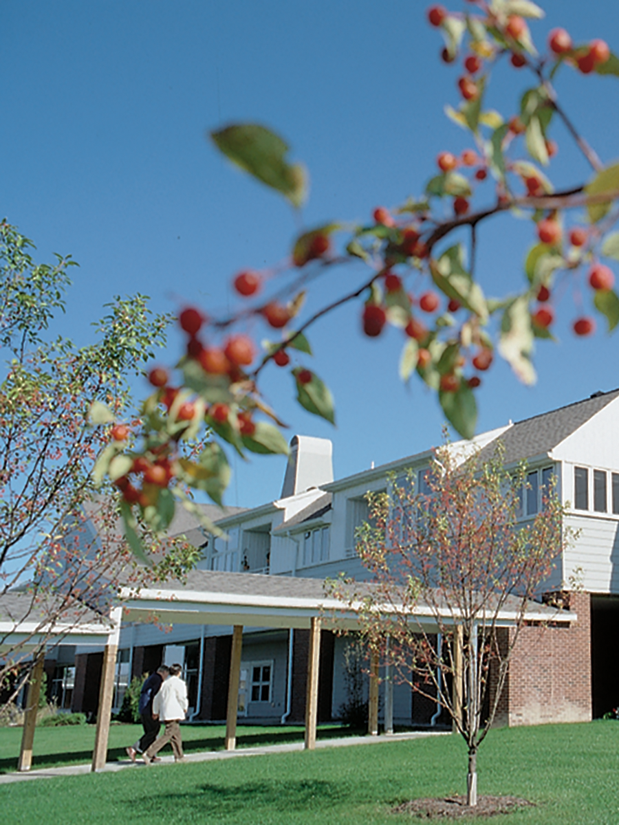 Residents walking in a landscaped outdoor area of the facility