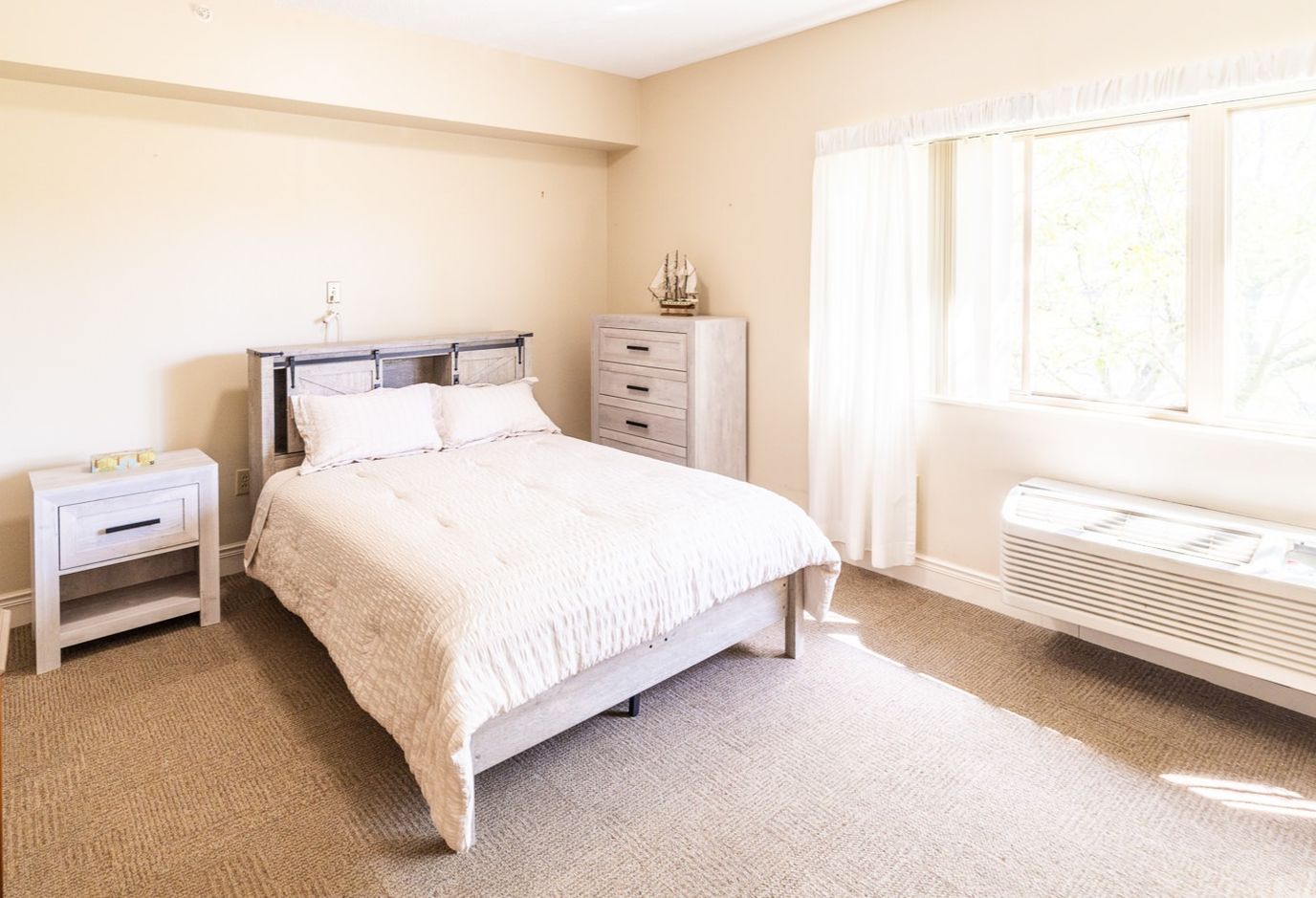 Heritage of Lyndhurst LLC, Nursing Home in Lyndhurst, OH — Cozy bedroom featuring a bed and dresser in natural light