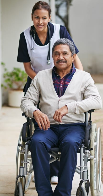 A nurse assisting a resident in a wheelchair outdoors.