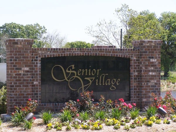 Senior Village Nursing & Rehabilitation Center, Nursing Home in Opelousas, LA — Brick sign with "Senior Village" surrounded by landscaping
