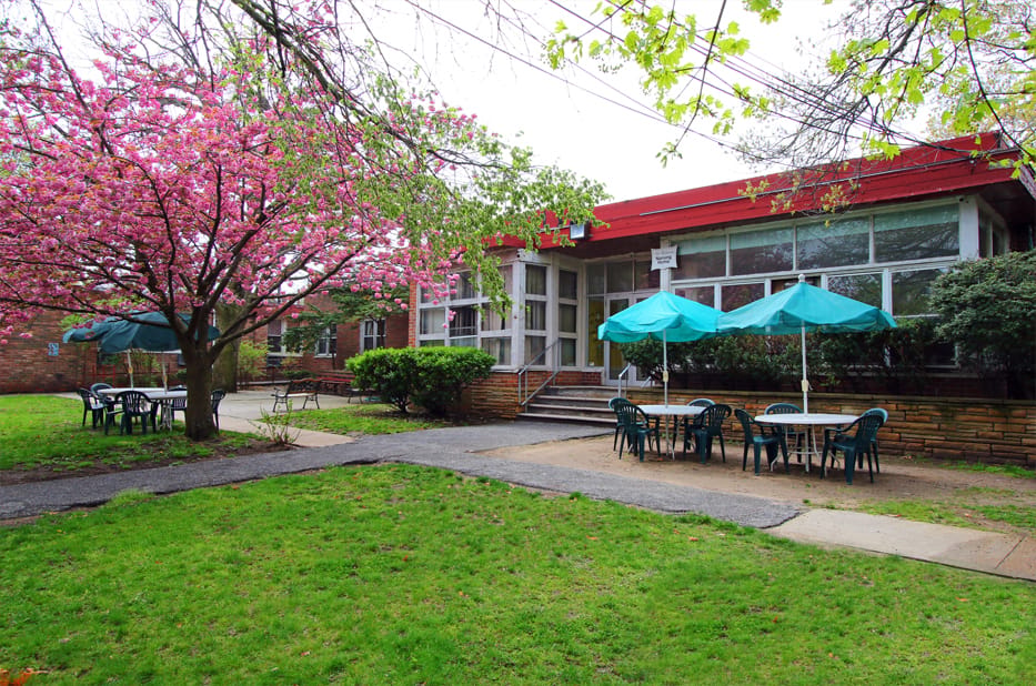Exterior view of a nursing home with outdoor seating and trees