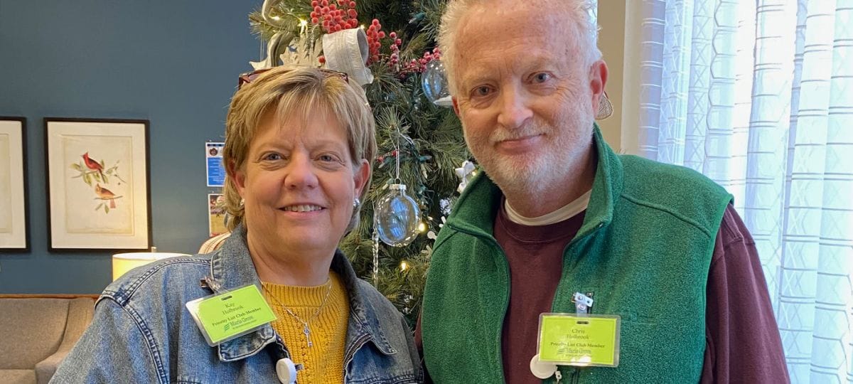 Two staff members posing near a decorated holiday tree