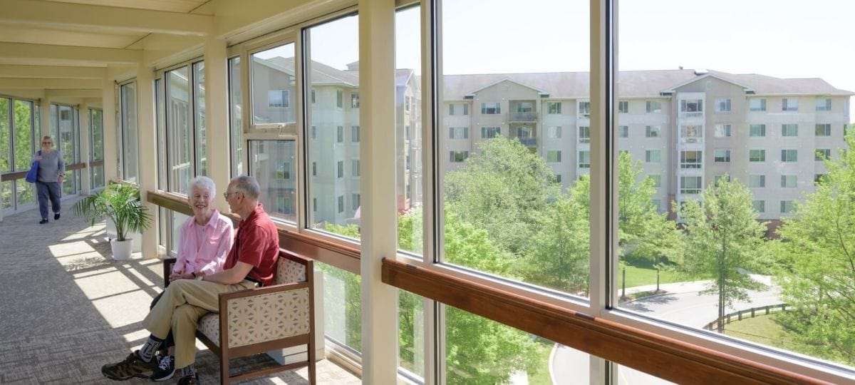 Residents enjoying a sunlit hallway with garden views