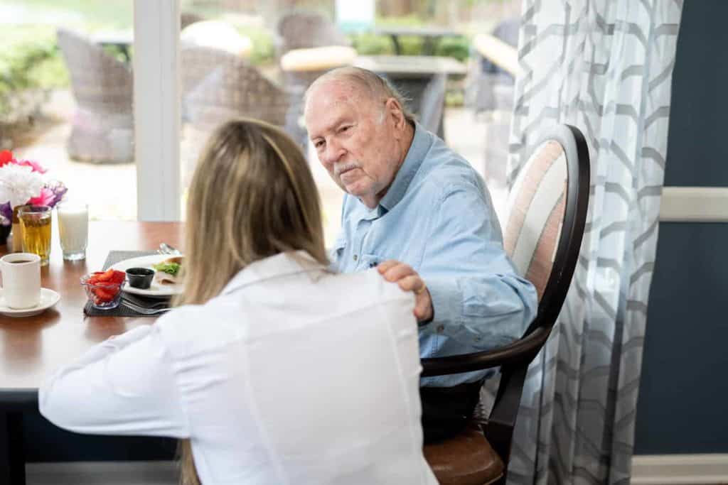 A resident enjoying a meal with staff in a dining area