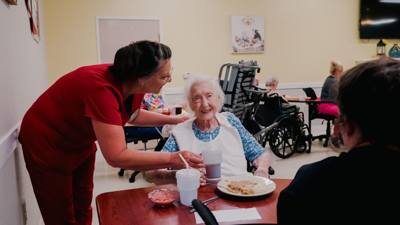 Resident enjoying a meal with staff assistance