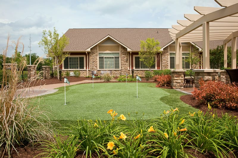 Outdoor putting green with colorful flowers and facility building