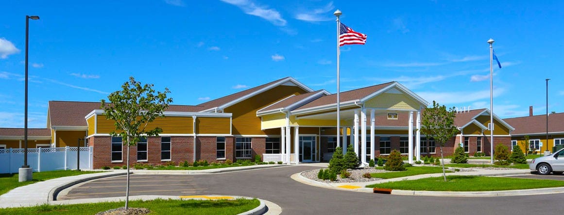Exterior view of the assisted living facility with flags and shrubs