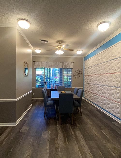 Bright common area with a dining table and decorative wall