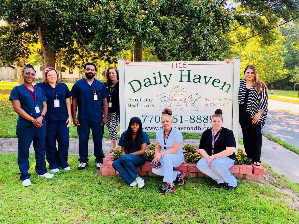 Staff members posing outside Daily Haven facility sign