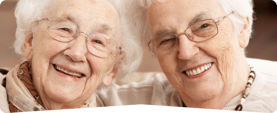 Trinity Care Adult Day Care Center, nursing home — Two smiling elderly women in a cozy setting