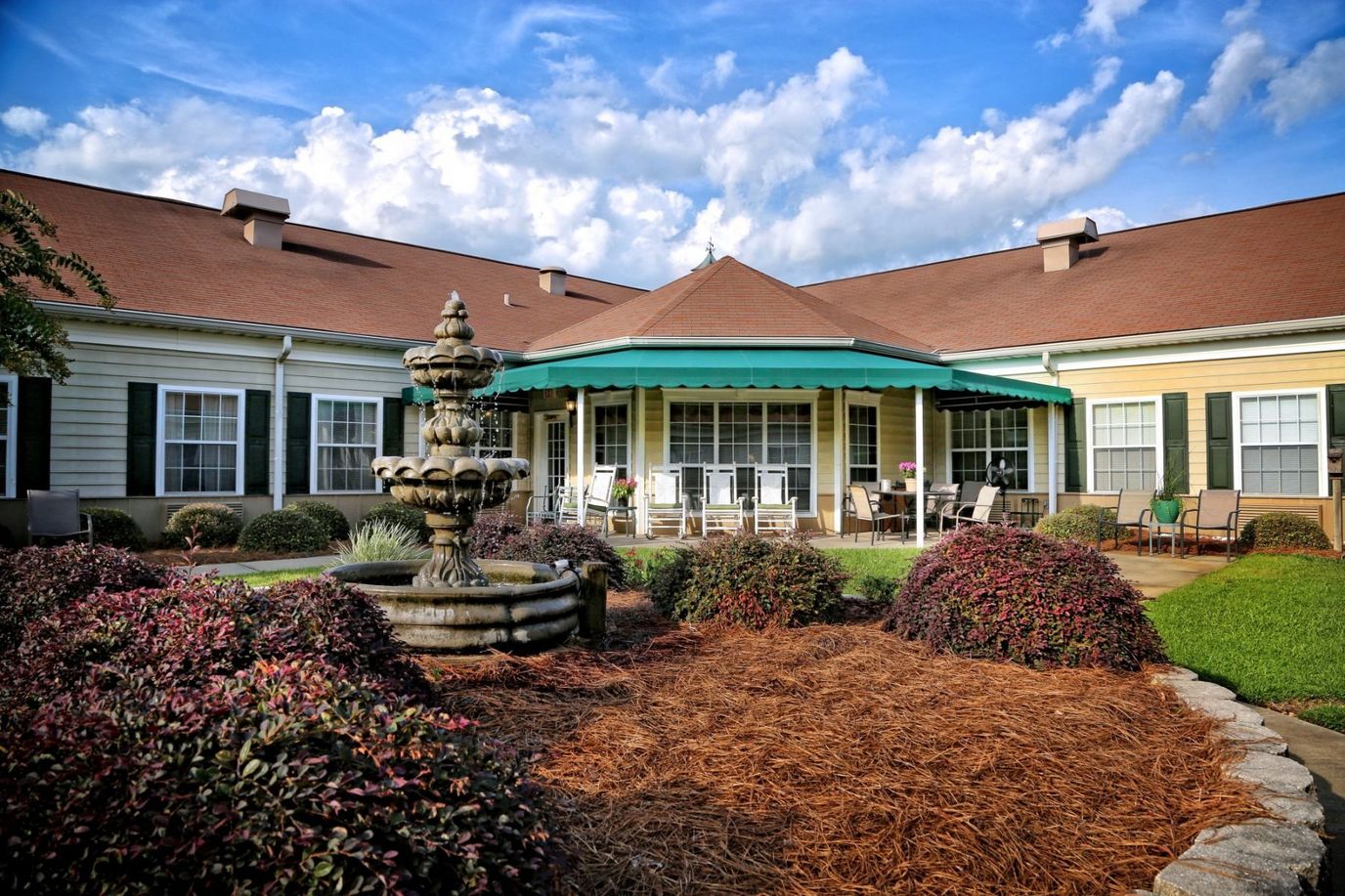 Exterior view of a senior residence with a fountain and gardens