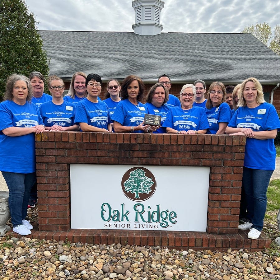 Staff members posing in front of the facility sign