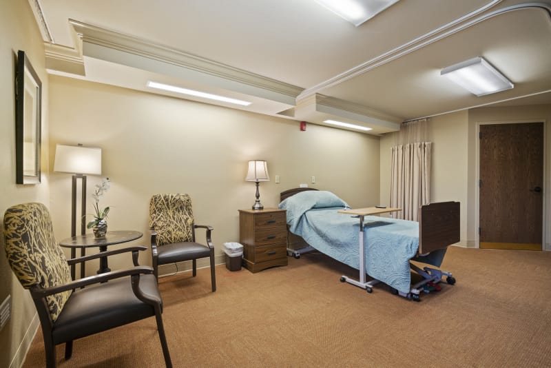 Heritage Manor of Ville Platte, Nursing Home in Ville Platte, LA — Cozy bedroom setup with a bed and armchairs