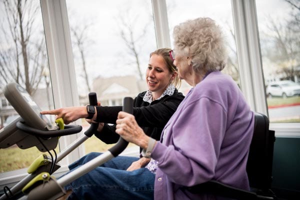 Staff assisting a resident on an exercise machine