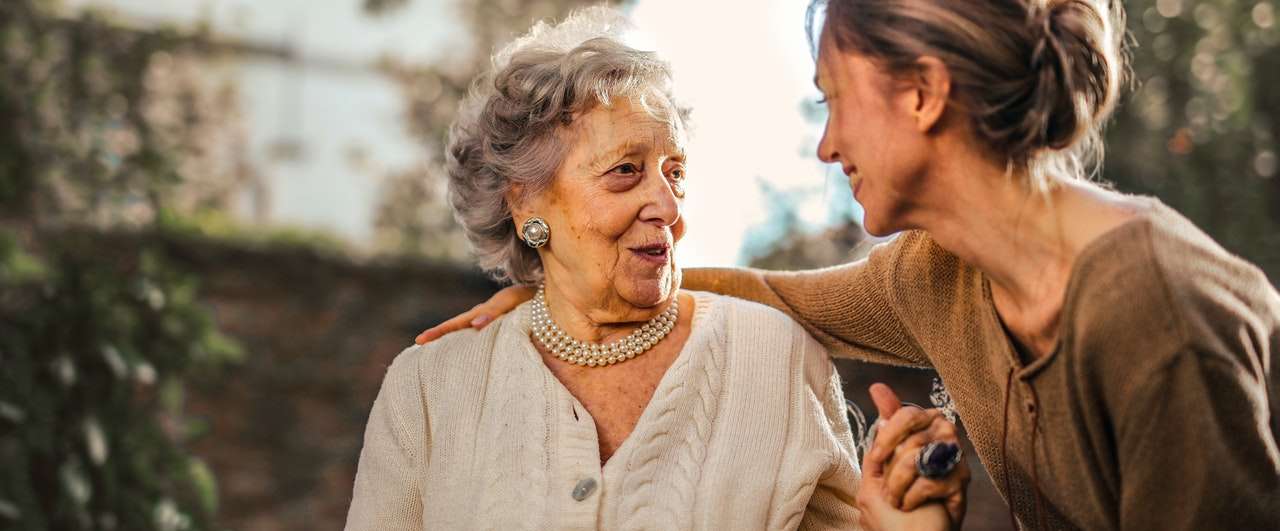Portland Center for Assisted Living, assisted living in Portland, ME — Two women enjoying a joyful conversation outdoors