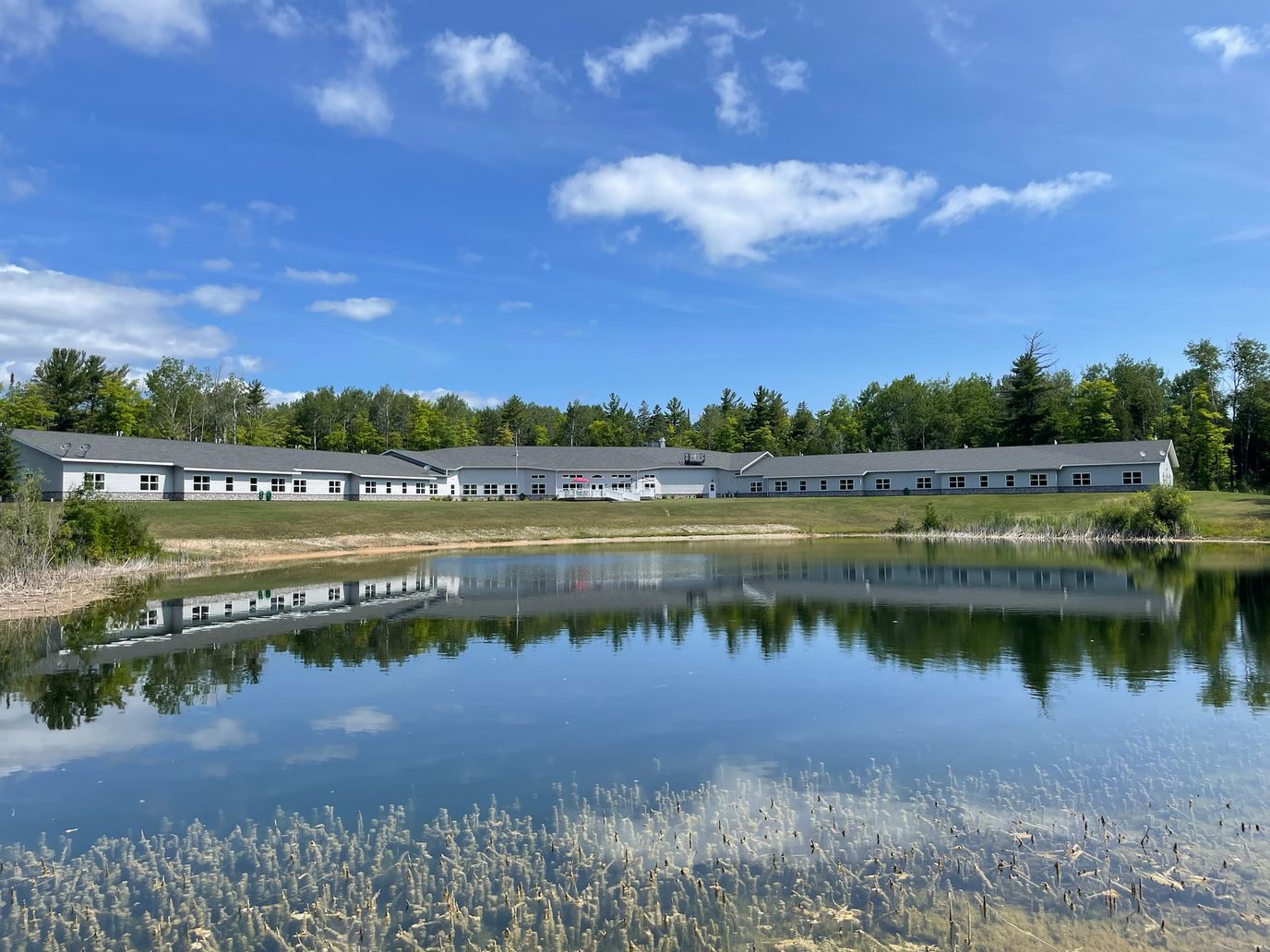 Exterior view of Straits Area Senior Living Community by a pond