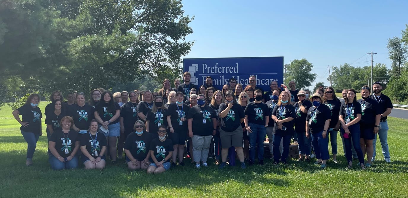 Group photo of staff outside the facility sign