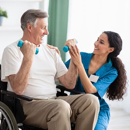 Mountainside of Warm Springs, assisted living in Warm Springs, GA — Senior man exercising with caregiver in wheelchair