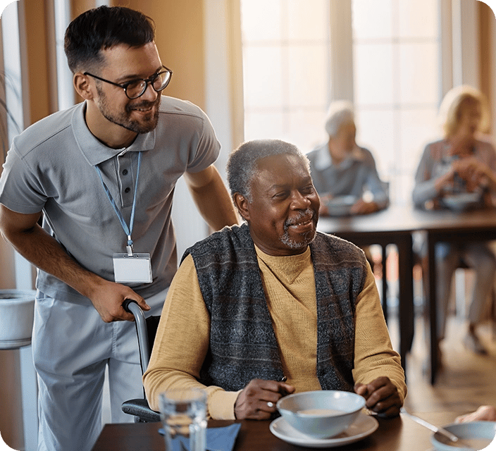 Staff assisting a smiling resident during mealtime.
