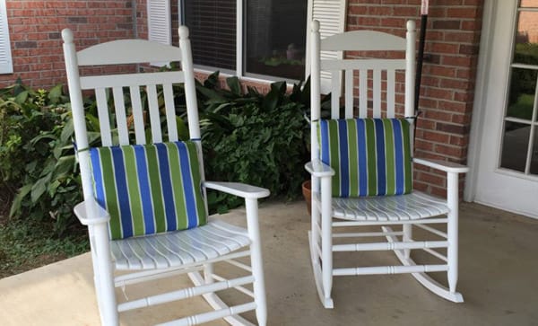 Two rocking chairs on a porch with greenery