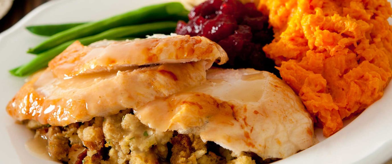 A plated meal featuring turkey, stuffing, and sweet potatoes