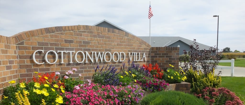 Entrance sign of Cottonwood Villa surrounded by flowers