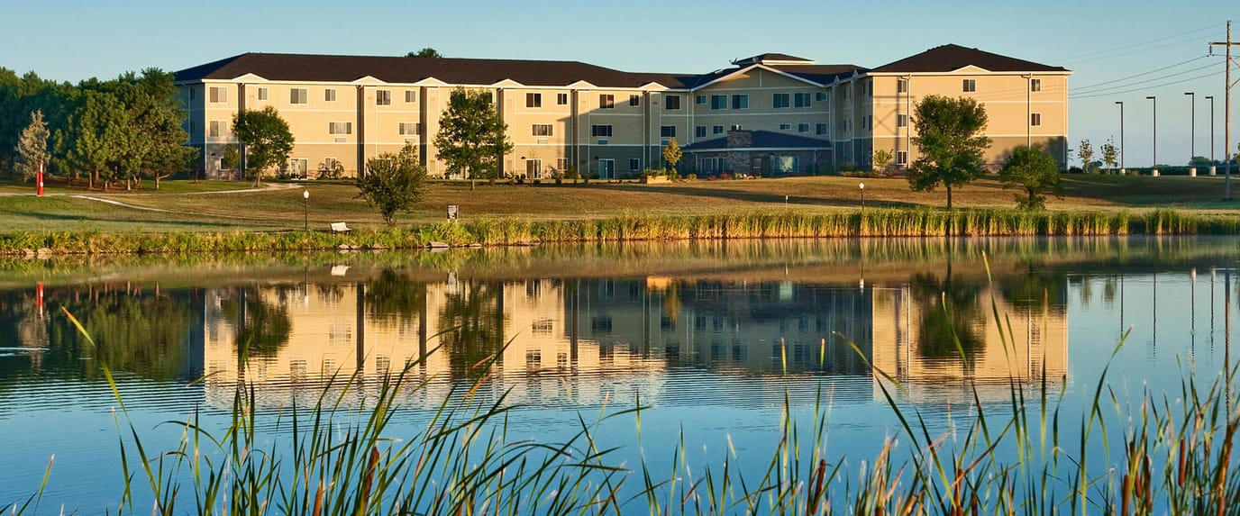 Exterior view of Oxbow Living Center by a reflective pond