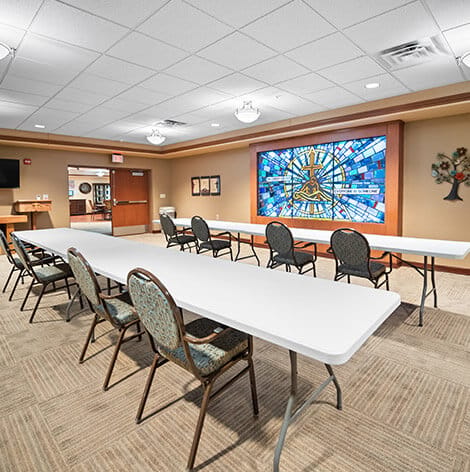 Good Samaritan Society – Grand Island Village, nursing home in Grand Island, NE — Activity room with chairs and a colorful stained glass window