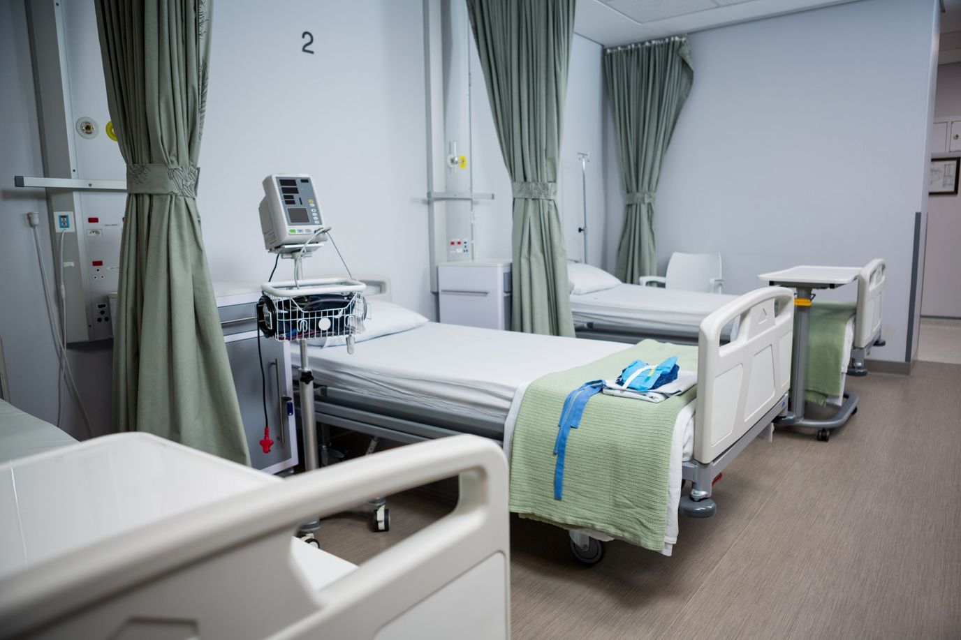 Empty hospital room with beds and medical equipment.