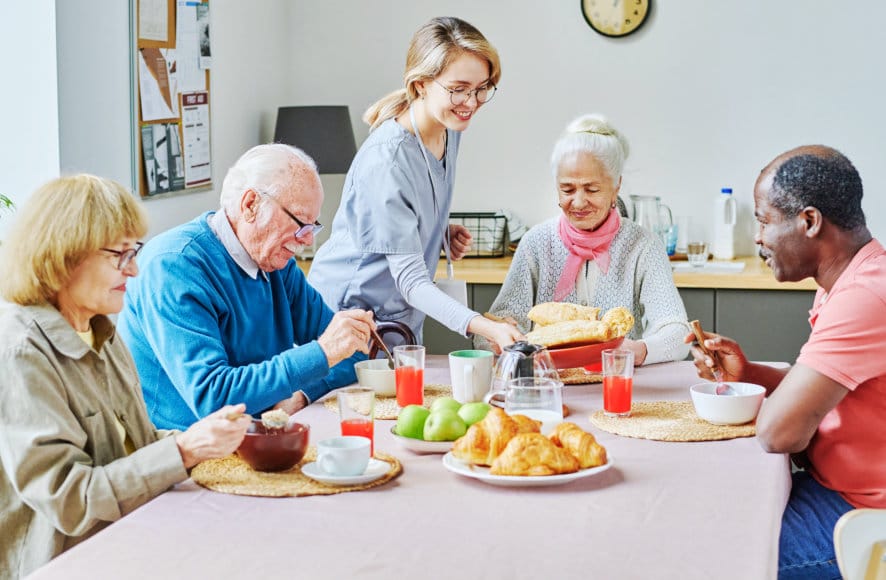 Residents enjoying a meal with staff assistance.