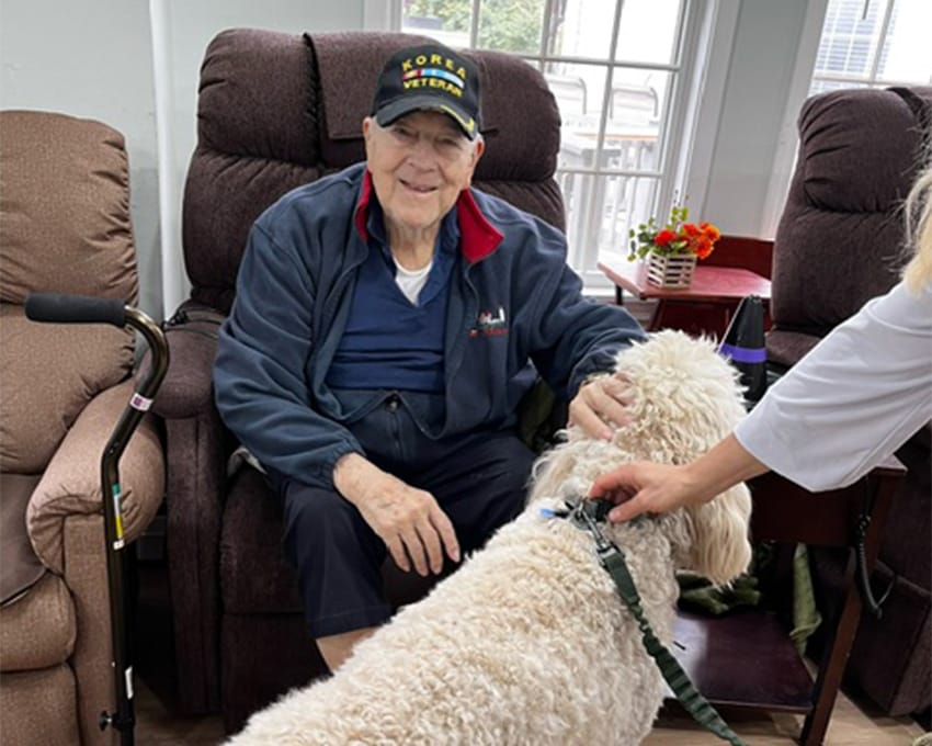 Resident with a dog in a cozy chairs area