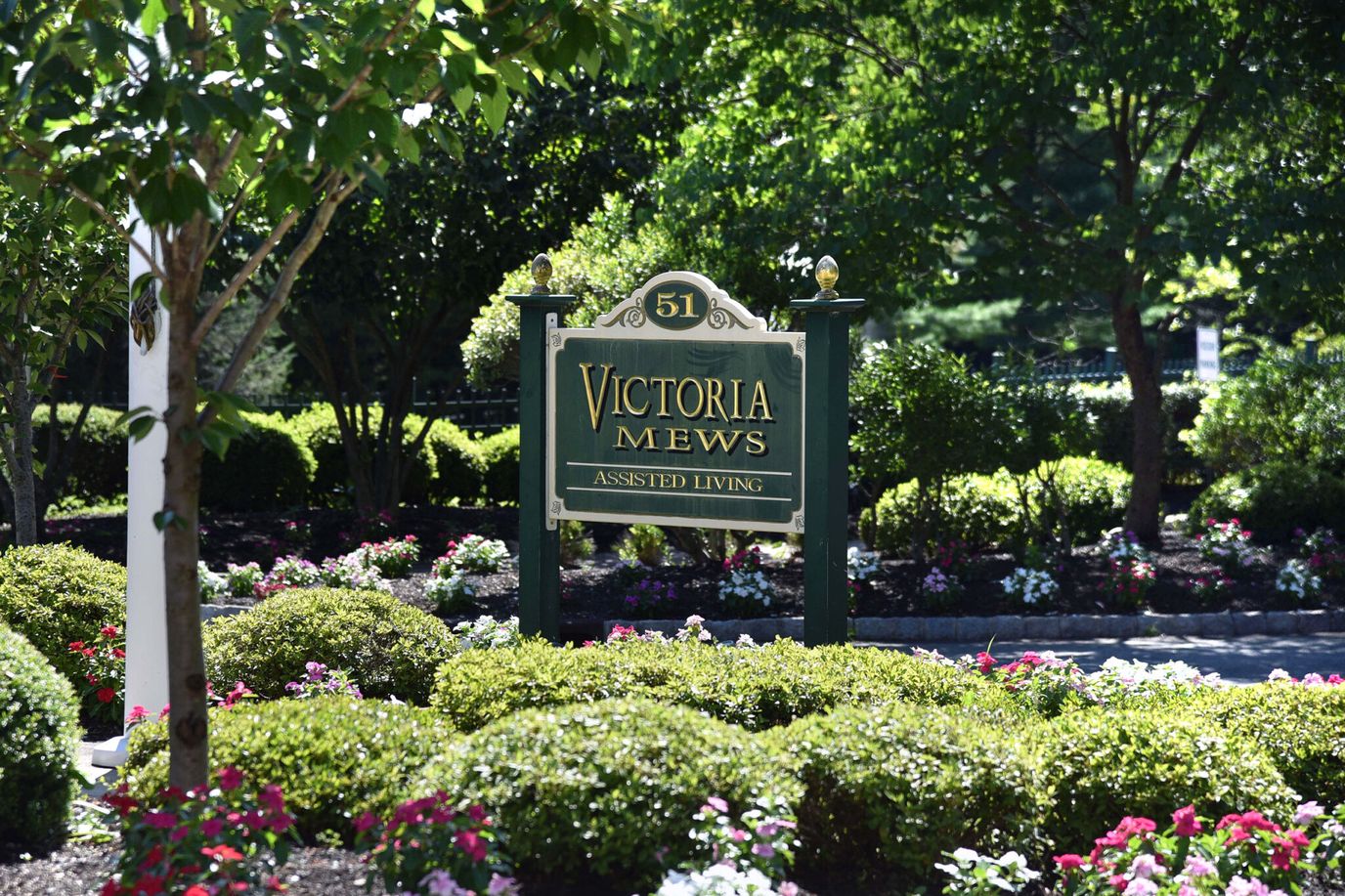 Sign for Victoria Mews Assisted Living surrounded by greenery