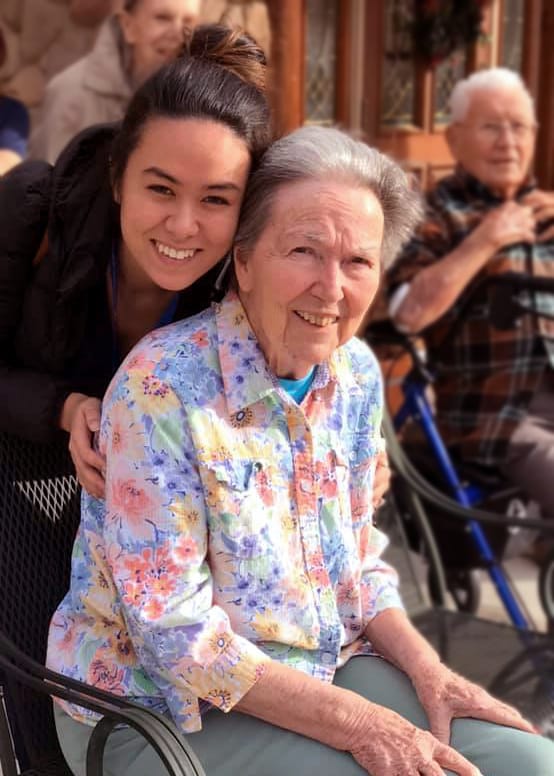 Resident and staff member smiling together outdoors